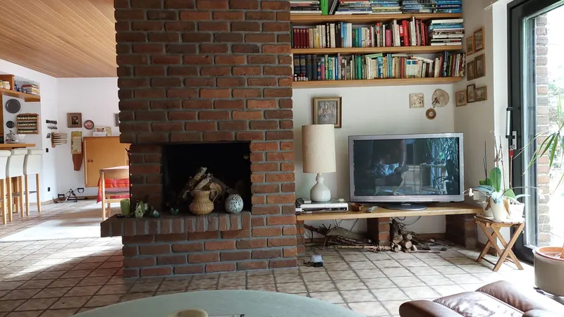 Salón con chimenea lleno de muebles y libros antes del vaciado en Maspalomas